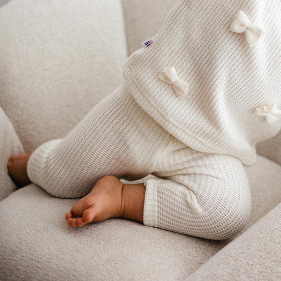 Fluffy Tails Legginsy niemowlęce Eevi  – sweterkowe ecru, z kokardką w pasie